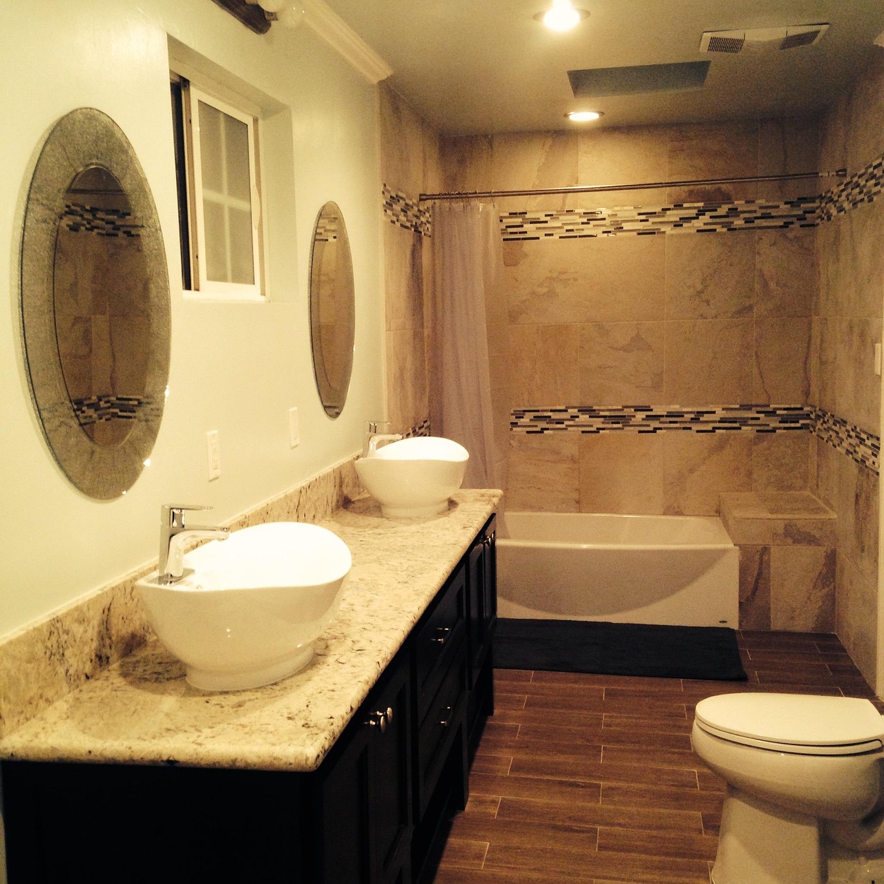 Bright remodeled bathroom with white tile, a glass shower and a gray vanity