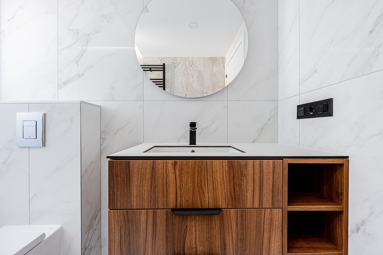 Clean white bathroom vanity with a round mirror